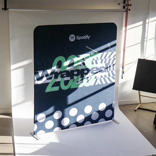 Same Day Roller Banners Printed in London, image shows them against a brick wall with an orange and green design 